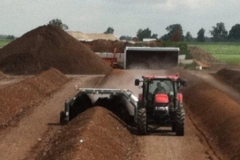 Turning a windrow of compost.
